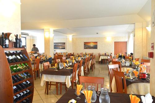 a restaurant with tables and chairs and wine bottles at Hotel Karin in Rimini