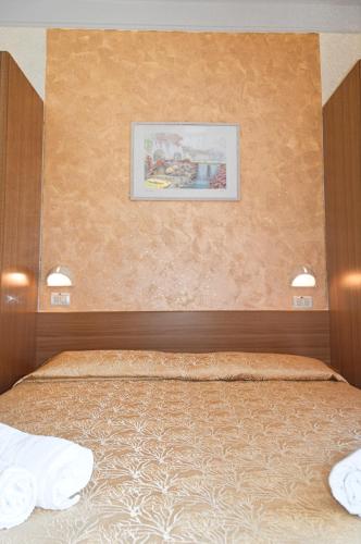a bedroom with a bed with a picture on the wall at Hotel Karin in Rimini