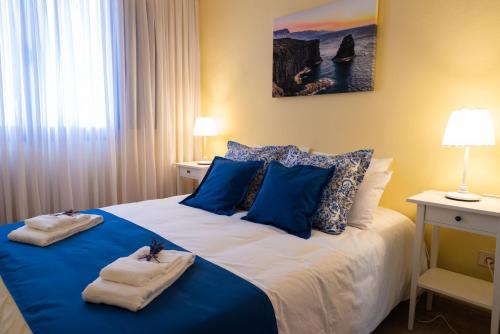 una camera da letto con un letto blu e bianco con asciugamani di Apartamento Vista Farallón a Gáldar