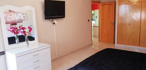 a room with a white dresser with a tv on the wall at Appartement de luxe centre ville les "Dunes d'Or" in Oujda