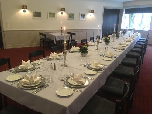 a long table in a room with tables and chairs at Hotel Rødding in Rødding