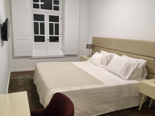 a bedroom with a white bed and a window at Casas Rosa Sousa in Felgueiras