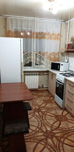 a kitchen with a table and a refrigerator and a stove at Apartment on Gogolya in Kostanay