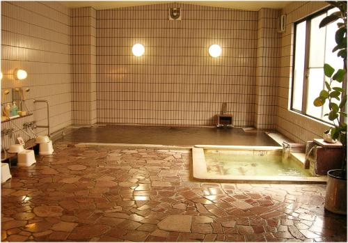 a large bathroom with a tub in the middle of a room at Hotel Yume-no-yu in Omachi