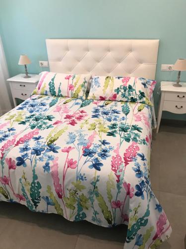 uma cama com colcha floral e duas mesas de cabeceira em APARTAMENTO AVENIDA 2 em Nerja