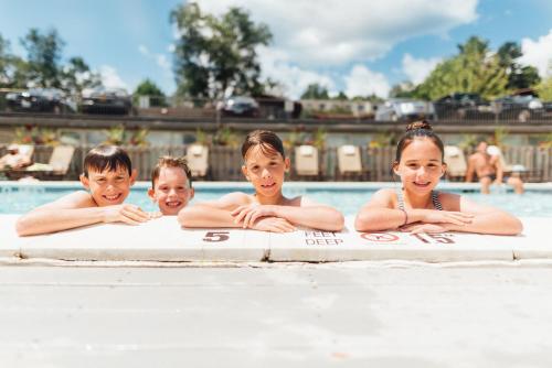 a group of children laying on a surfboard in a swimming pool at Lake House at High Peaks Resort in Lake Placid