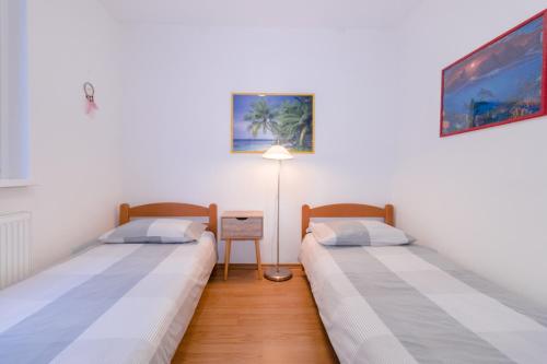 two twin beds in a room with a lamp at Fredi in Piran