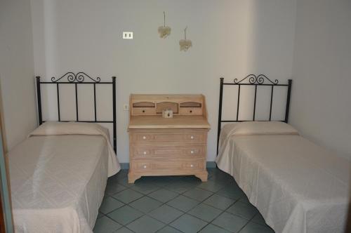 two beds with a wooden dresser in a room at Appartamento Li Puntiti 3 in Budoni