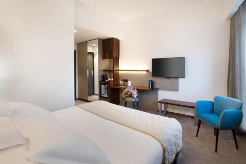 a hotel room with a bed and a blue chair at Best Western Plus Hotel & Restaurant Les Humanistes Colmar Nord in Sélestat