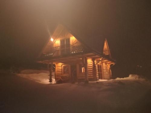 una baita di tronchi nella neve di notte di Domek "Pod Lubaniem" a Grywałd