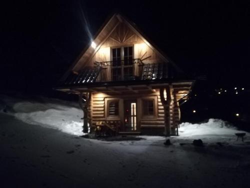 eine Holzhütte im Schnee in der Nacht in der Unterkunft Domek "Pod Lubaniem" in Grywałd