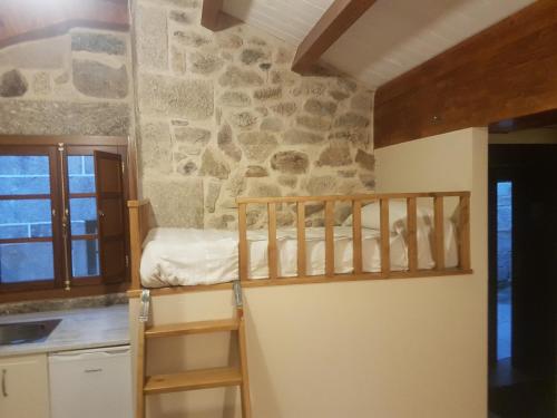 een slaapkamer met een stapelbed en een stenen muur bij Casa Mariñeira in Combarro