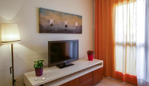 a living room with a flat screen tv on a cabinet at Leo Punta Umbría in Punta Umbría