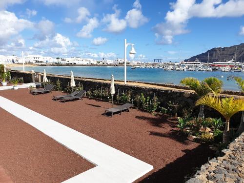 a row of benches next to the water with a harbor at La Graciosa Magnolia Evita Beach, Frente Mar in Caleta de Sebo