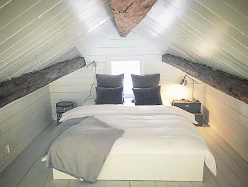 a bedroom with a white bed in a attic at The Boathouse in Råkvåg