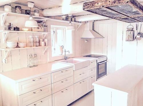 a white kitchen with white counters and white cabinets at The Boathouse in Råkvåg