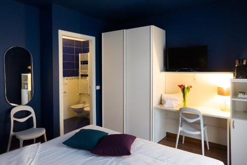 a bedroom with a bed and a desk and a bathroom at Albergo Residenza Al Teatro in Udine