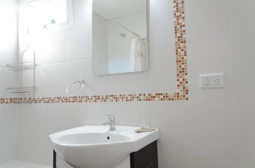 a white bathroom with a sink and a mirror at Flamenco Bay Apartments in El Calafate