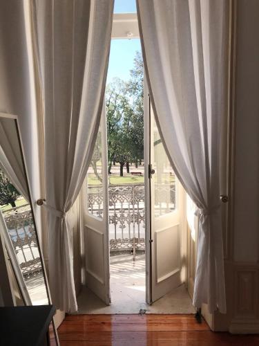 an open door with curtains open to a porch at Hotel Jardim in Coimbra