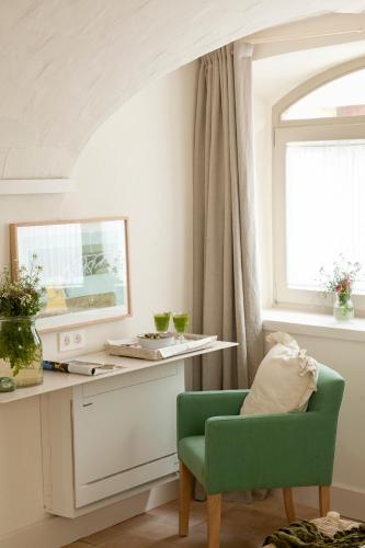 a living room with a green chair and a desk at Arkhé Hotel Boutique Pals in Pals