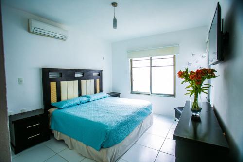 um quarto com uma cama com lençóis azuis e uma janela em Casa moderna en segura Residencial Hacienda Chetumal em Chetumal