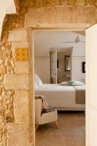 a bedroom with a bed and a stone wall at Arkhé Hotel Boutique Pals in Pals