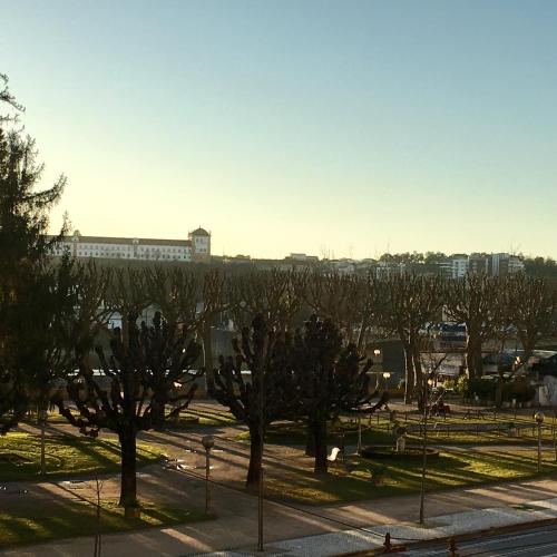 a park with trees and a building in the background at Hotel Jardim in Coimbra
