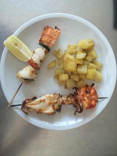 a plate of food with fish and potatoes and a slice of lemon at Villa Liliana in Cervia