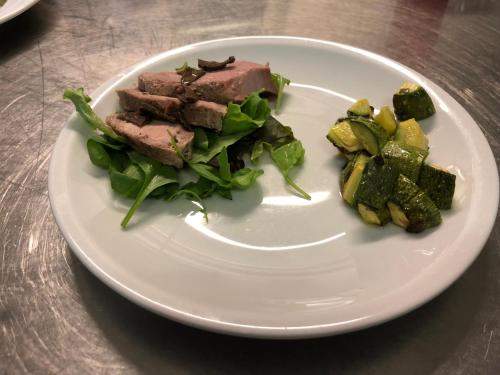 a plate of food with meat and vegetables on a table at Villa Liliana in Cervia