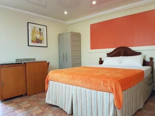 a bedroom with a large bed with an orange blanket at Maria Mulata Apartments in Noord