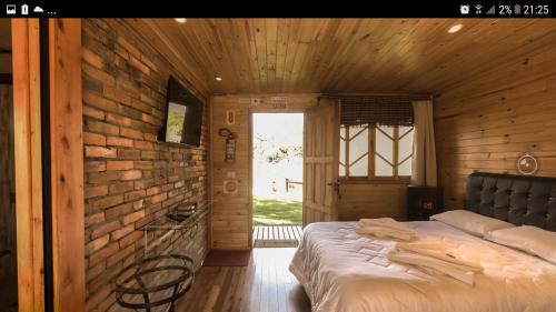 a bedroom with a bed in a wooden wall at Pousada Cajuvá in Urubici