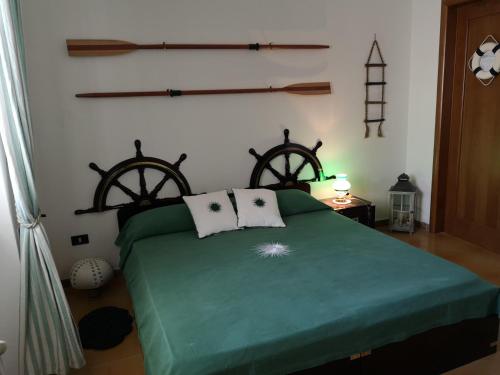 a bedroom with a green bed with two iron wheels on the wall at B&B Villa Ines in Leuca