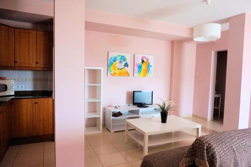 sala de estar con paredes rosas y mesa blanca en La Graciosa Magnolia Evita Beach, Frente Mar, en Caleta de Sebo