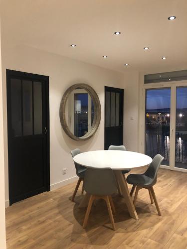 a dining room with a table and chairs and a mirror at L'Escale Sètoise in Sète