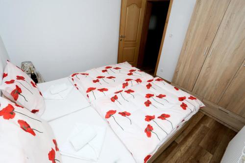 a bed with red flowers on it in a room at Apartmani Mila in Laktaši