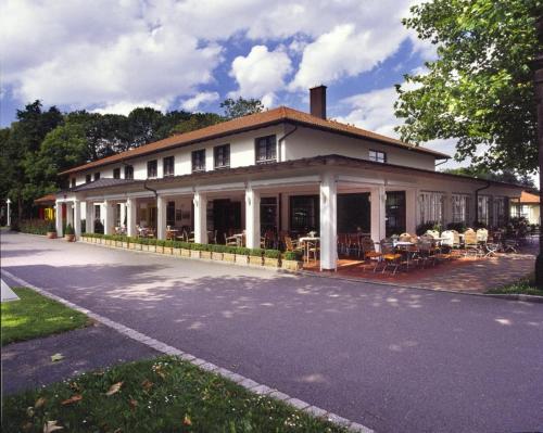 a large white building with tables and chairs on a street at Kim Hotel Im Park in Dresden