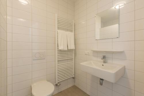 een witte badkamer met een toilet en een wastafel bij Welcome in - Aparthotel Zoutelande Luxe Studio 2 personen - 1 huisdier toegestaan in Zoutelande