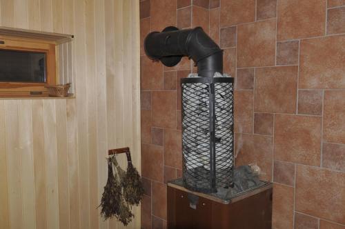 a wood stove in a room with a tiled wall at Svenceles 25 sodyba Namas su pirtimi ir krantine in Svenele