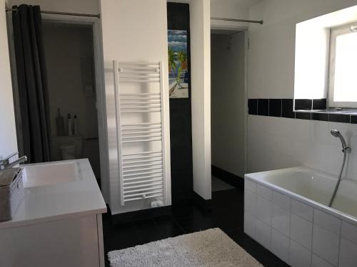 une salle de bain blanche avec une baignoire et un lavabo dans l'établissement Gîte Du Bourrelier, à Boutenac