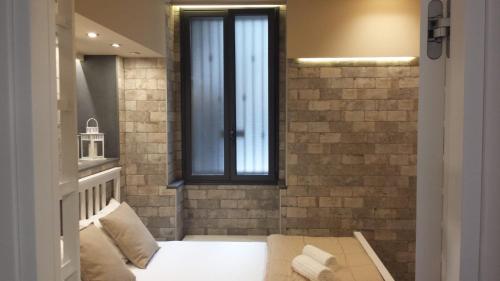 ein Schlafzimmer mit einem Fenster in einer Ziegelwand in der Unterkunft VENTIMIGLIA SUITE & WINE in Catania