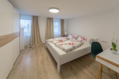 ein weißes Schlafzimmer mit einem Bett, einem Tisch und einem Fenster in der Unterkunft Bodensee Ferienwohnung Claudia 4 in Friedrichshafen