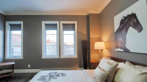 a bedroom with a bed with a horse picture on the wall at INITIAL - CAVALIER - Chutes-Montmorency in Boischâtel