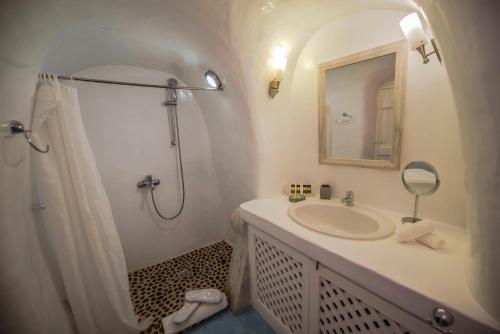 a white bathroom with a sink and a shower at Marizan Caves & Villas in Oia