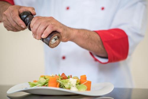 a chef pouring a bottle of wine over a plate of food at Hotel Lomas del Volcan in Fortuna