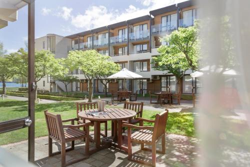 a patio with a table and chairs and a building at Novotel Queenstown Lakeside in Queenstown