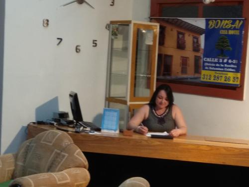 a woman sitting at a desk in an office at Bonsai Hotel Salamina Caldas in Salamina