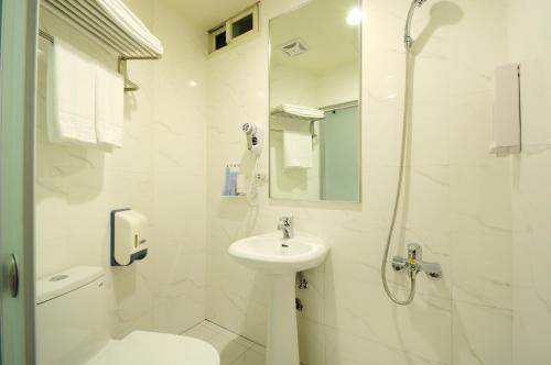 a white bathroom with a sink and a shower at Bravo Hotel in Taichung