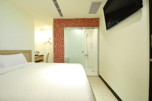 a bedroom with a white bed and a shower at Bravo Hotel in Taichung