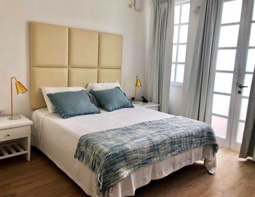 a bedroom with a large bed with two blue pillows at Casa Paracas in Paracas