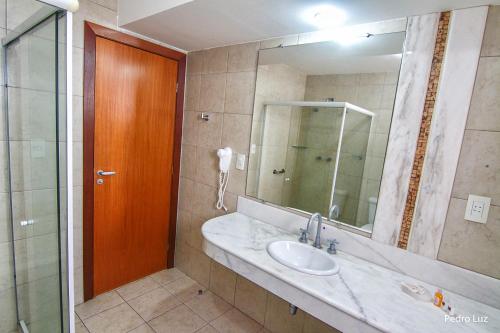 a bathroom with a sink and a mirror and a phone at River Park Hotel in Resende